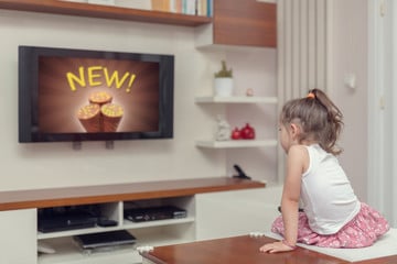 cute little girl watching advertisement on tv